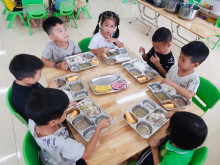 Các bé mẫu giáo 5 tuổi ăn trưa bằng khay suất ăn riêng