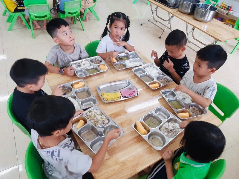 Các bé mẫu giáo 5 tuổi ăn trưa bằng khay suất ăn riêng